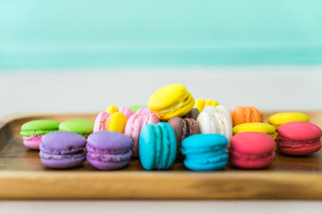 soft focus of  Colorful Pastel Macarons in wooden dish on table with green wall background