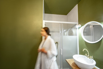 Beautiful loft interior bathroom with motion blurred woman figure in bathrobe walking out the shower