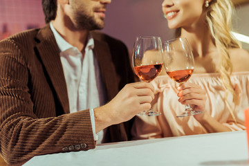 partial view of couple clinking by wine glasses during date at table in cafe
