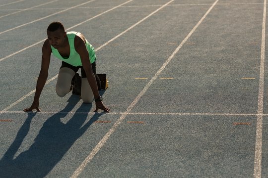 Male athlete in starting position on running track