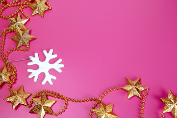 White snowflake and necklace of golden stars for Christmas decoration on the pink background. Christmas and New Year holiday background concept. Copy space for text.