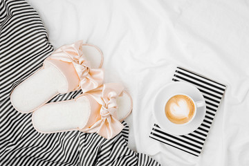 Bedding sheets with book and coffee cup. Flat lay, top view