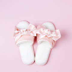 Stylid female slippers with bow on pale pink  background. Flat lay, top view
