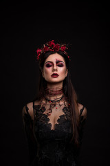 Portrait of a girl in the image for Halloween.  Wreath of roses. Closed eyes. Makeup for halloween. Black background.