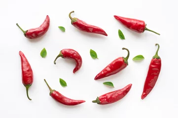 Keuken spatwand met foto Red hot chili peppers met groene bladeren op een witte achtergrond. Voedsel patroon. © masterq