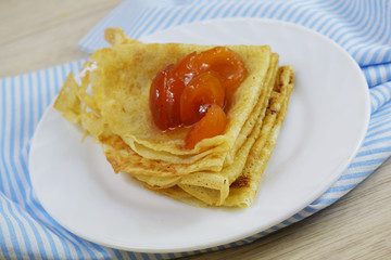 Delicious hot pancakes with apricot jam on a white plate.