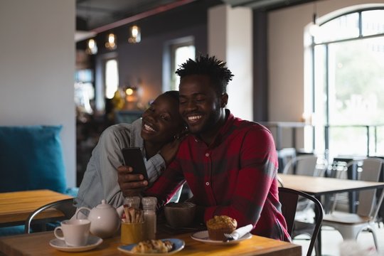 Smiling young couple taking selfie in cafe