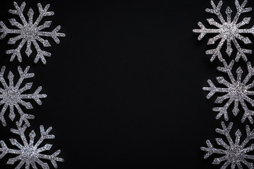 Silver glittering snowflake Christmas decorations on black background with copy space