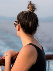 Young woman on ship fence looking at the sea