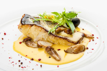 Pike perch with porcini mushrooms and potatoes. On a white plate