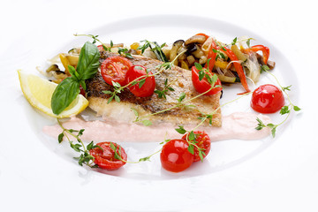 Pike perch with vegetables on a white dish.