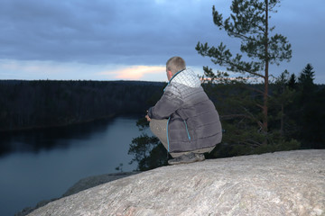 Fototapeta na wymiar man sitting on a rock and looking at the lake