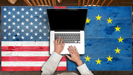 USA and Europe flagged wooden Table with laptop in restaurant