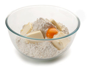 Bowl de cristal ovalado con un huevo, mantequilla y harina en su interior