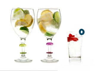 Dos copas y un vaso de cristal con hielos y frutas en su interior