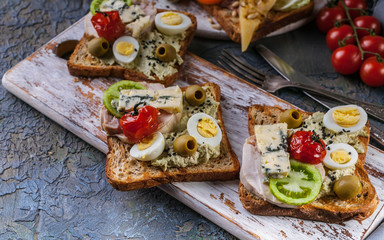 Appetizing toasts of avocado, meatloaf, quail eggs, tomatoes and Dor Blue cheese. Author's cuisine. Original serving dishes