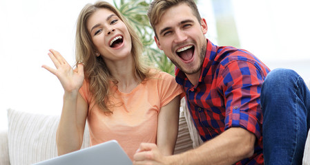 young couple rejoices,sitting on the couch in front of the open laptop