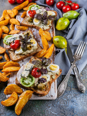 Appetizing toasts with avocado, quail eggs, tomatoes, Dor Blue cheese and french fries. Author's cuisine. Original serving dishes