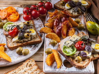 Appetizing toasts with avocado, quail eggs, tomatoes, Dor Blue cheese and french fries. Author's...