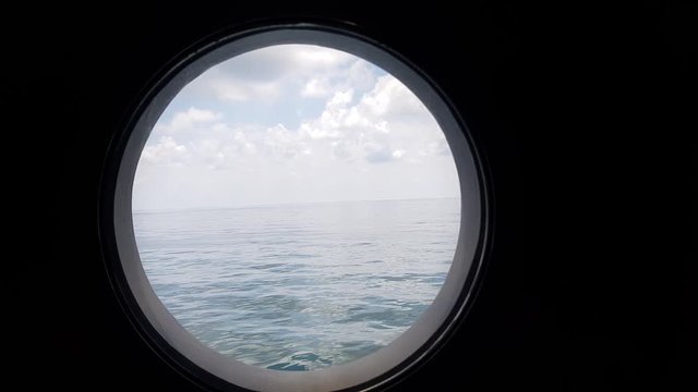 peaceful view through porthole of a sailing vessel in calm seas at sunset