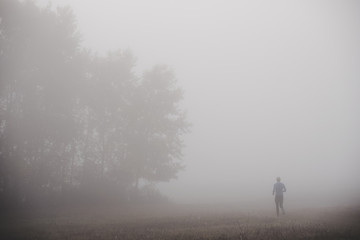 Fototapeta na wymiar Runner silhouette in blue autumn morning mist