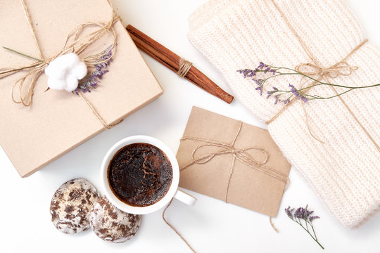 Craft envelope, gift box with bow, knitted scarf, dried flowers and leaves, cup of coffee, cinnamon sticks, gingerbread on white background. Winter, holiday concept. Flat lay, top view, copy space