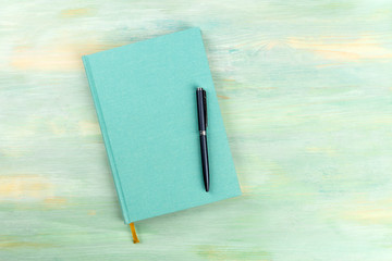 A photo of a blue journal with a pen, an elegant diary, notebook or planner, shot from the top on a...