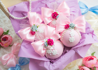 winter vacation. New Year's toys made by hand. a set of pink Christmas balls with a bow of satin ribbon, lace, flowers lies in a box with purple paper.
