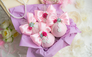 winter vacation. New Year's toys made by hand. a set of pink Christmas balls with a bow of satin ribbon, lace, flowers lies in a box with purple paper.