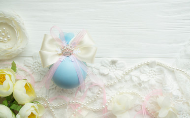 Fototapeta na wymiar winter vacation. New Year's toys made by hand. Christmas ball in blue color with a bow of satin ribbon, lace, brooch crown, flowers lies on a white wooden background