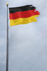 Worn and tattered German flag blowing in the wind on a cloudy day