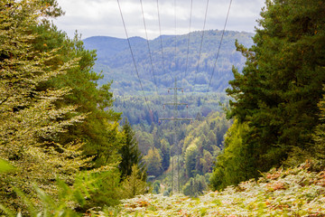 Power lines going through a rural forest landscape area with hills to reach tiny villages without proper electricity coverage 