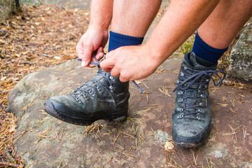 Close up of a man tying his hiking shoes on a trip outside in the forest
