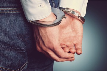Cropped image of male hands in handcuffs behind his back