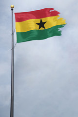 Worn and tattered Ghana flag blowing in the wind on a cloudy day
