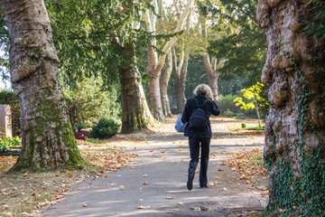 Unidentified woman in black walking in a park on the way to a burial of a loved one of her family