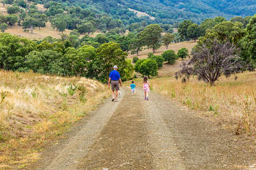 Grandfather walking with his grandchildren and a dog, along a path in the Upper Hunter Valley, NSW, Australia.