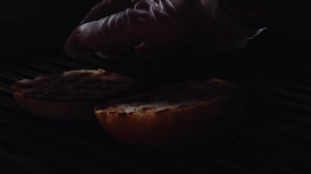 Chef preparing the burger, frying the bun on the grill. Cook turns over the buns for burger on a grill.