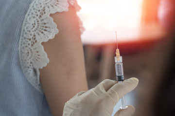 World immunization week and International HPV awareness day concept. Woman having vaccination for influenza or flu shot or HPV prevention with syringe by nurse or medical officer.