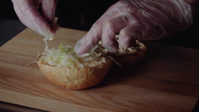 Chef making burger. frying the bun on the grill, putting the Lettuce