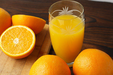 Oranges and a glass of orange juice on a wooden table.