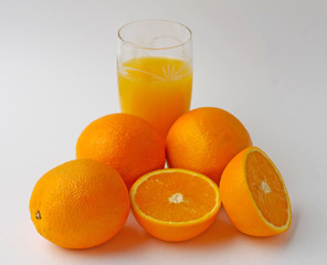 Oranges and a glass of orange juice on a white background.