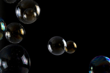 Multicolored soap bubbles close up on a black background, similar to planets
