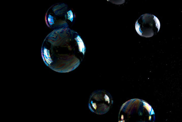 Multicolored soap bubbles close up on a black background, similar to planets