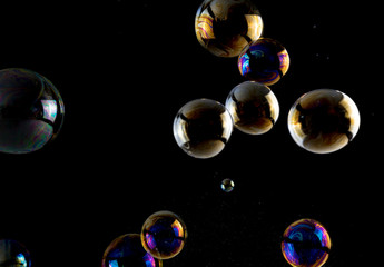 Multicolored soap bubbles close up on a black background, similar to planets