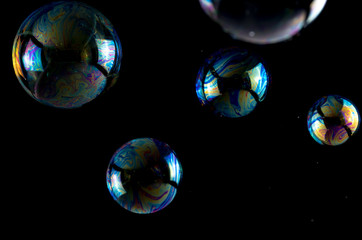 Multicolored soap bubbles close up on a black background, similar to planets
