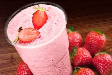 Glass of strawberry smoothie on wooden table