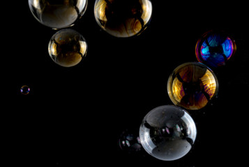 Multicolored soap bubbles close up on a black background, similar to planets