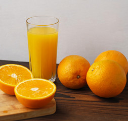 Oranges and a glass of orange juice on a wooden table.