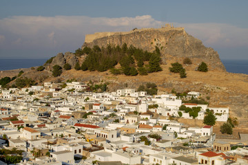 The whitewashed buildings of the village of Lindos,Rhodes,Greece dominated by the ancient Acropolis...